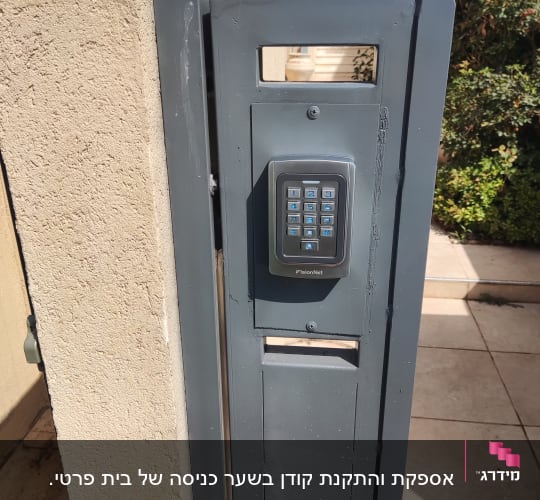 אינטרקום עם לוח מקשים על שער מתכת אפור